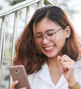 woman laughing while looking at her phone