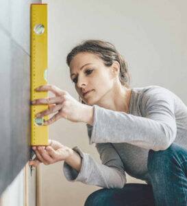 Woman balancing and measuring a wall