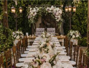 Elegant outdoor wedding reception table with white flowers and candlelit lanterns